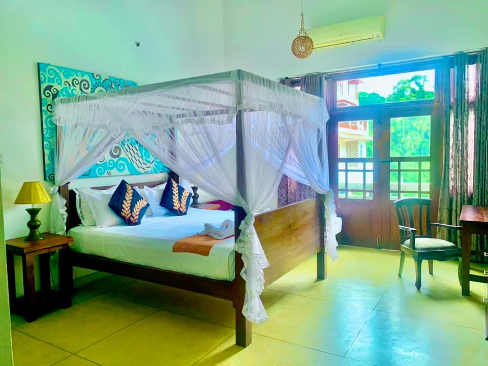 Gangula Villa room with four-poster canopy bed and batik headboard artwork