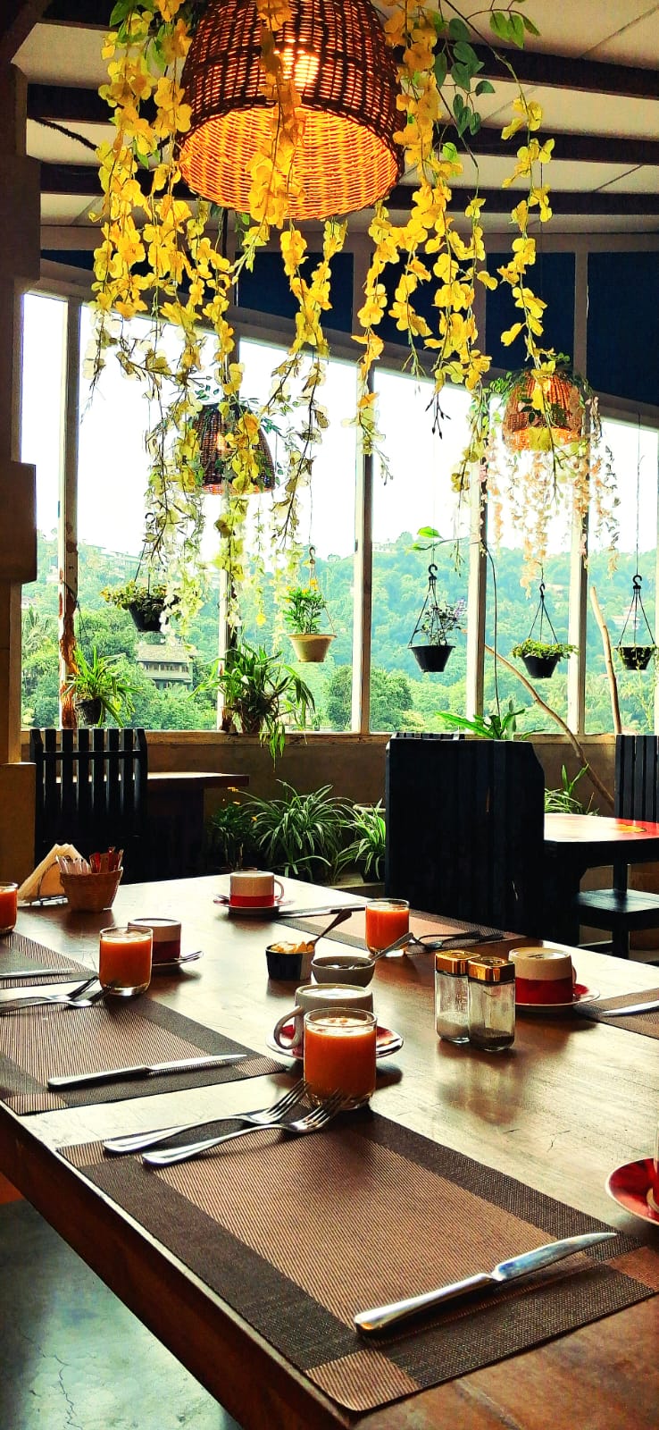 Gangula Villa restaurant breakfast table set with fresh juice, overlooking the Kandy hill-country through flower-draped windows